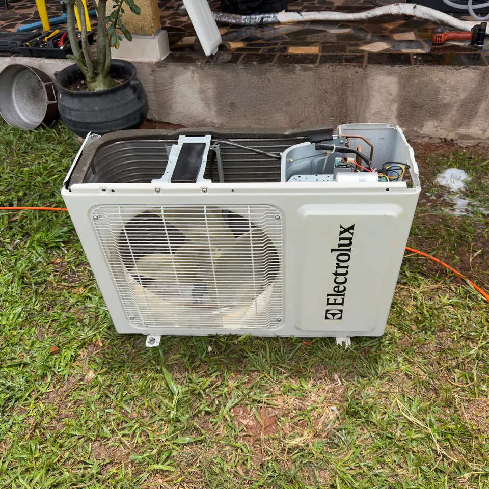 Condensadora Electrolux limpa, aberta sobre a grama durante o serviço.